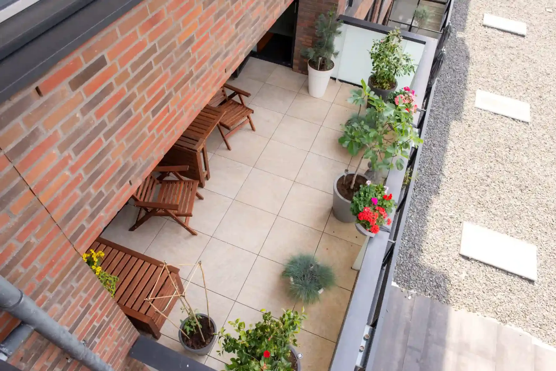 balkon met planten en bruine meubels op een licht roze vloer