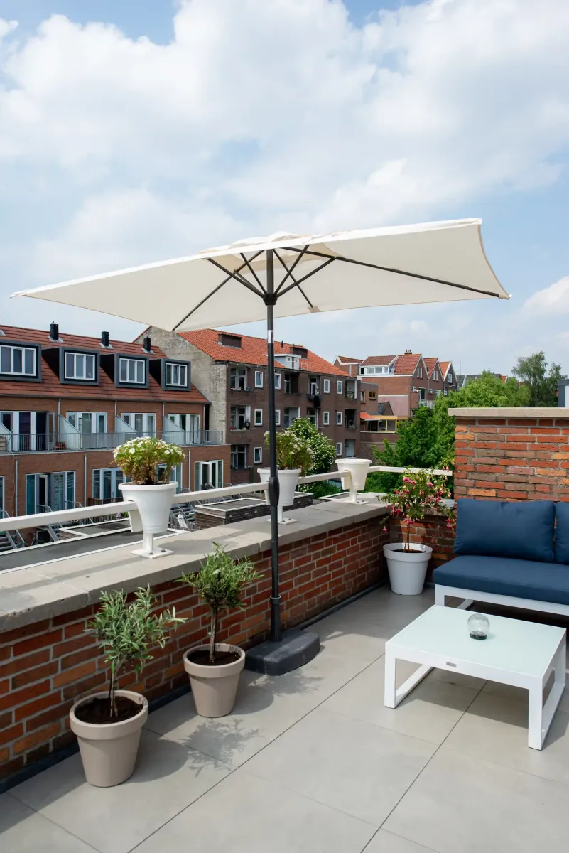 modern dakterras met lichte tegels en een parasol